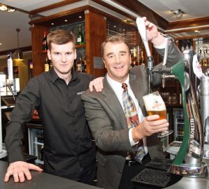 Nigel Mansell pulls a pint behind the bar at Nineteen57 with chef manager, Sion Wellings