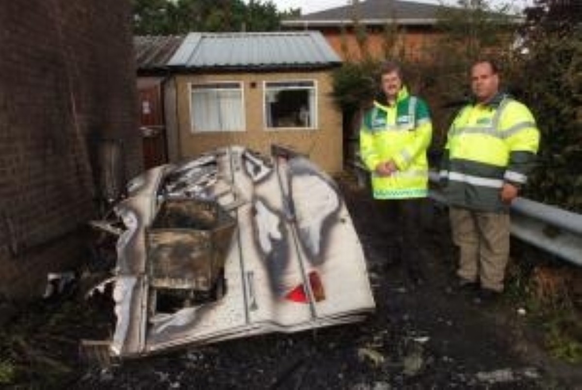 Emergency services stand by a burnt-out caravan