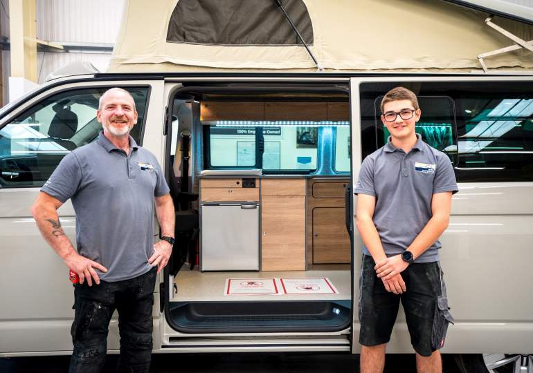 Carpenter and apprentice stand outside campervan