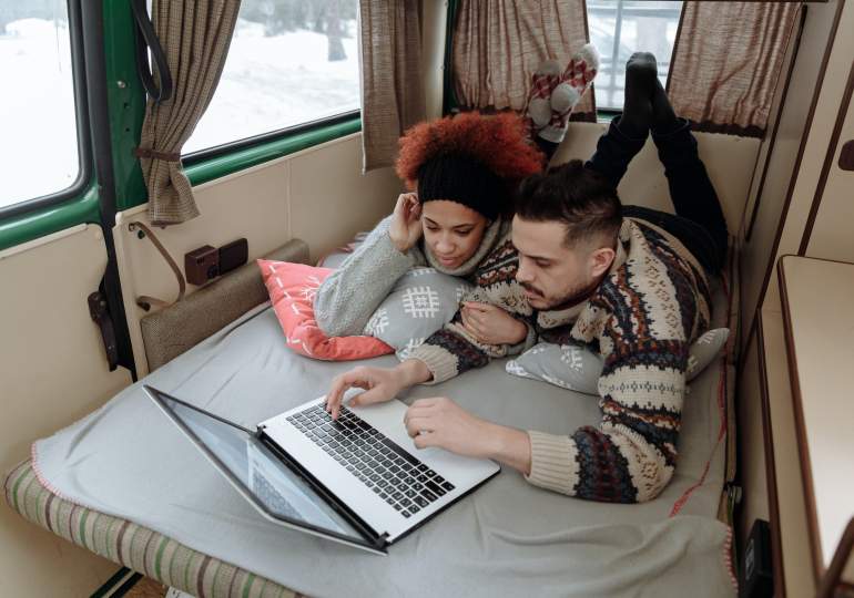 Couple checking out Black Friday deals on a laptop in their motorhome