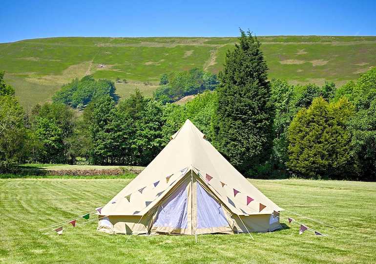 Bell tent in a field with a blue sky