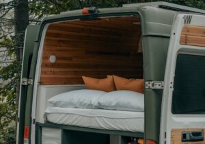 A campervan with its doors open, exposing the bed set up.