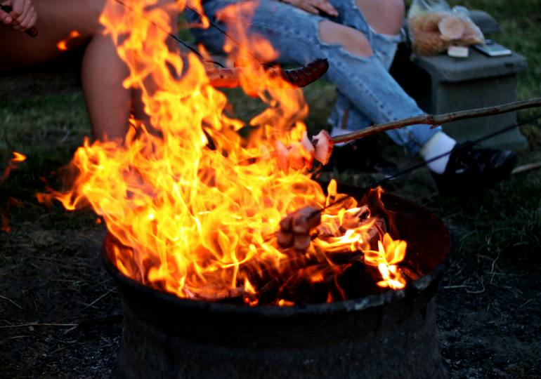 People toasting food on a campfire