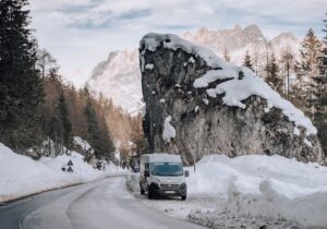 A converted van in front of snowy mountains
