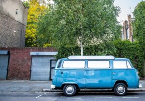 A blue campervan parked up outside a house