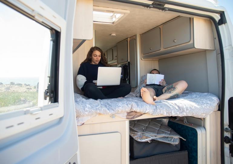 A couple watching TV in the back of a camper van