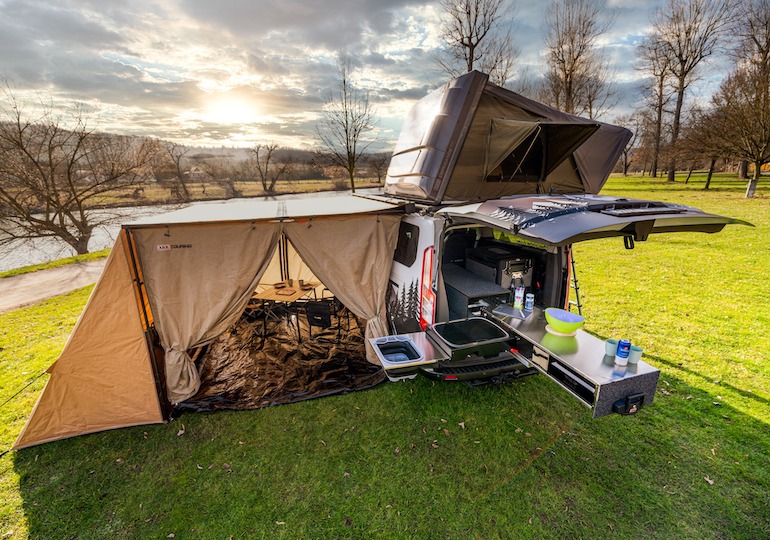 An aerial view of a converted van, rooftop tent and awning