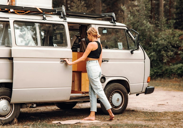A young woman opening the door to a campervan