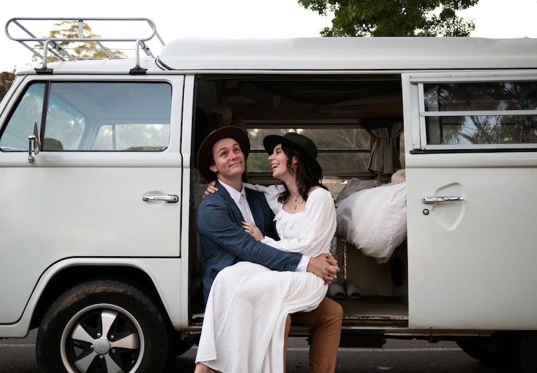 A couple embracing while sitting on the doorstep to a camper van
