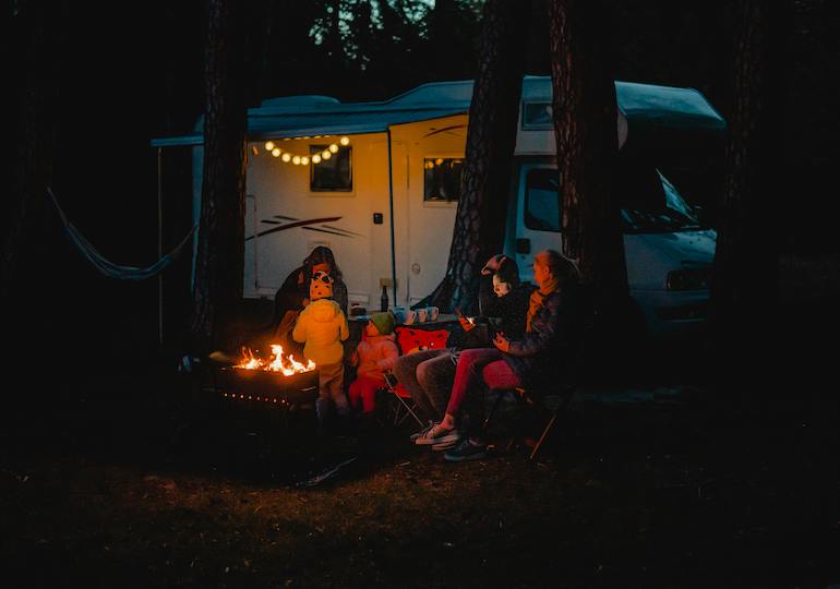 A family around a campfire outside their motorhome