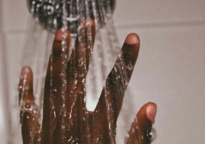 A hand reaching up to a shower head