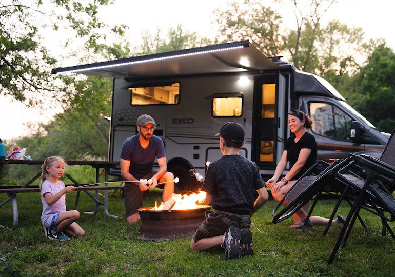 Family enjoying a campfire outside their RV