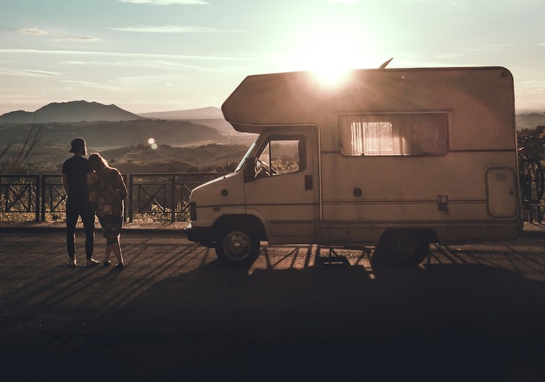 Couple standing next to a motorhome as the sun sets