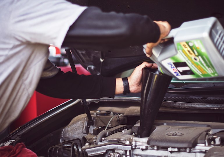 A man topping up fluids in a car