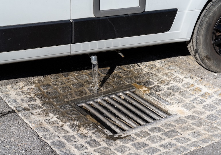 A close up view of proper disposal of gray water and waste water from a camper van at an RV park