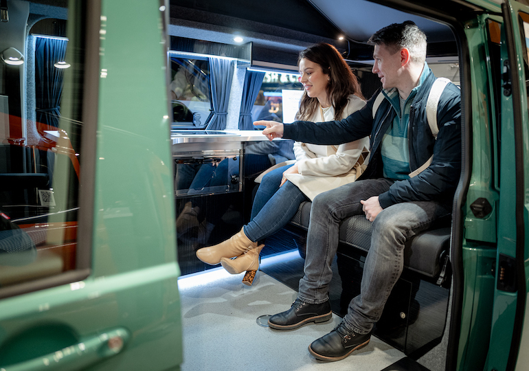 Two people sitting inside a campervan at a show