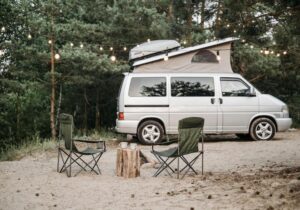 A campervan with a pop-top roof and camping chairs set up outside