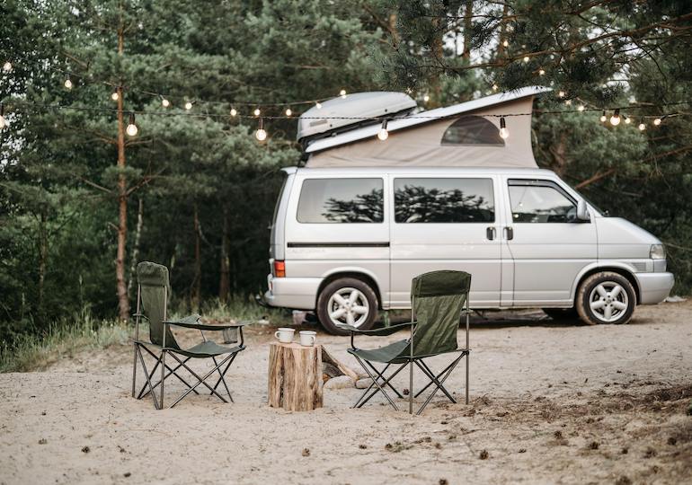 A campervan with a pop-top roof and camping chairs set up outside